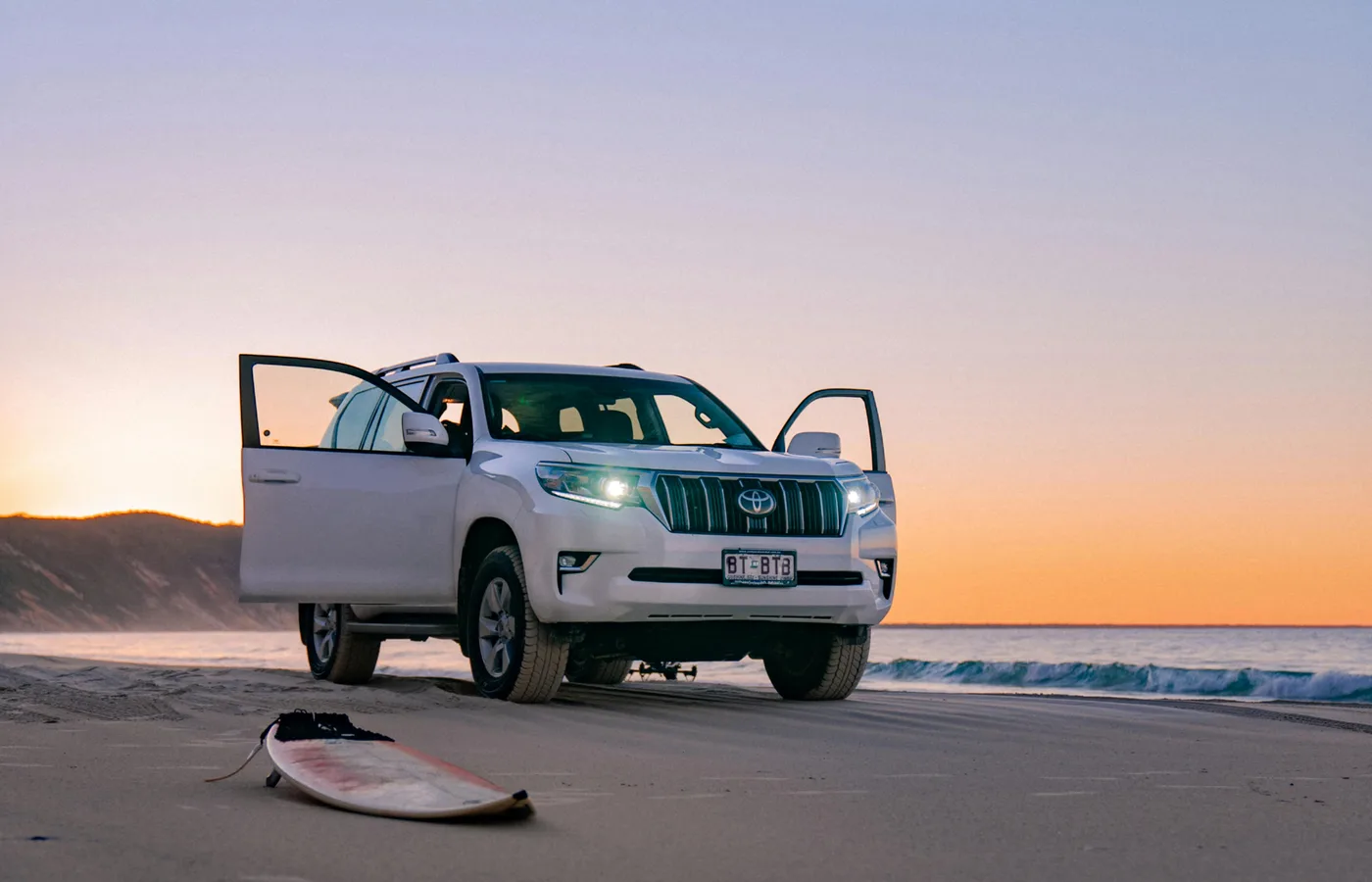 4WD vehicle parked on a Queensland beach at sunset.